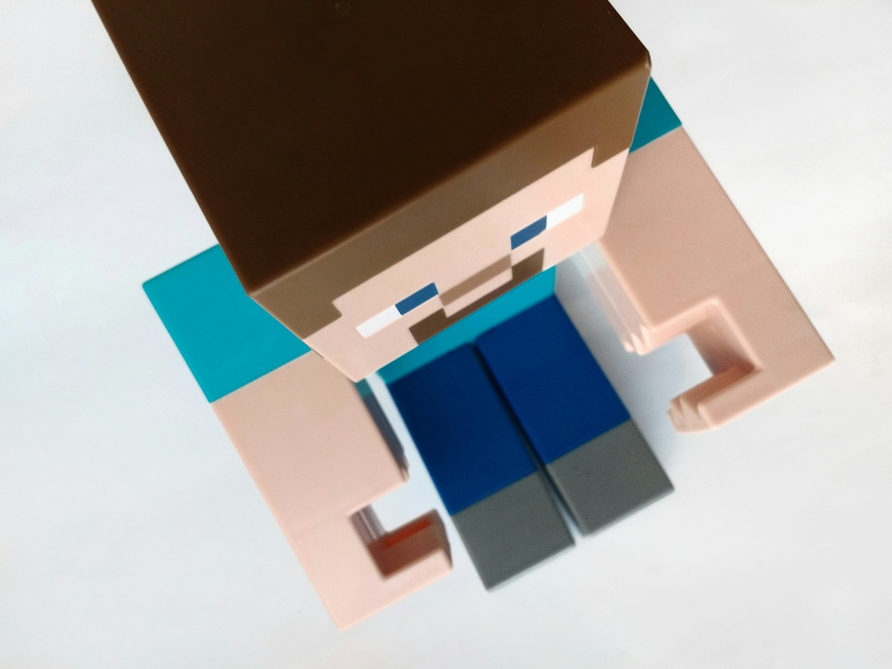 白色背景中的Minecraft人物玩具，方块身体展示低分辨率视觉语法